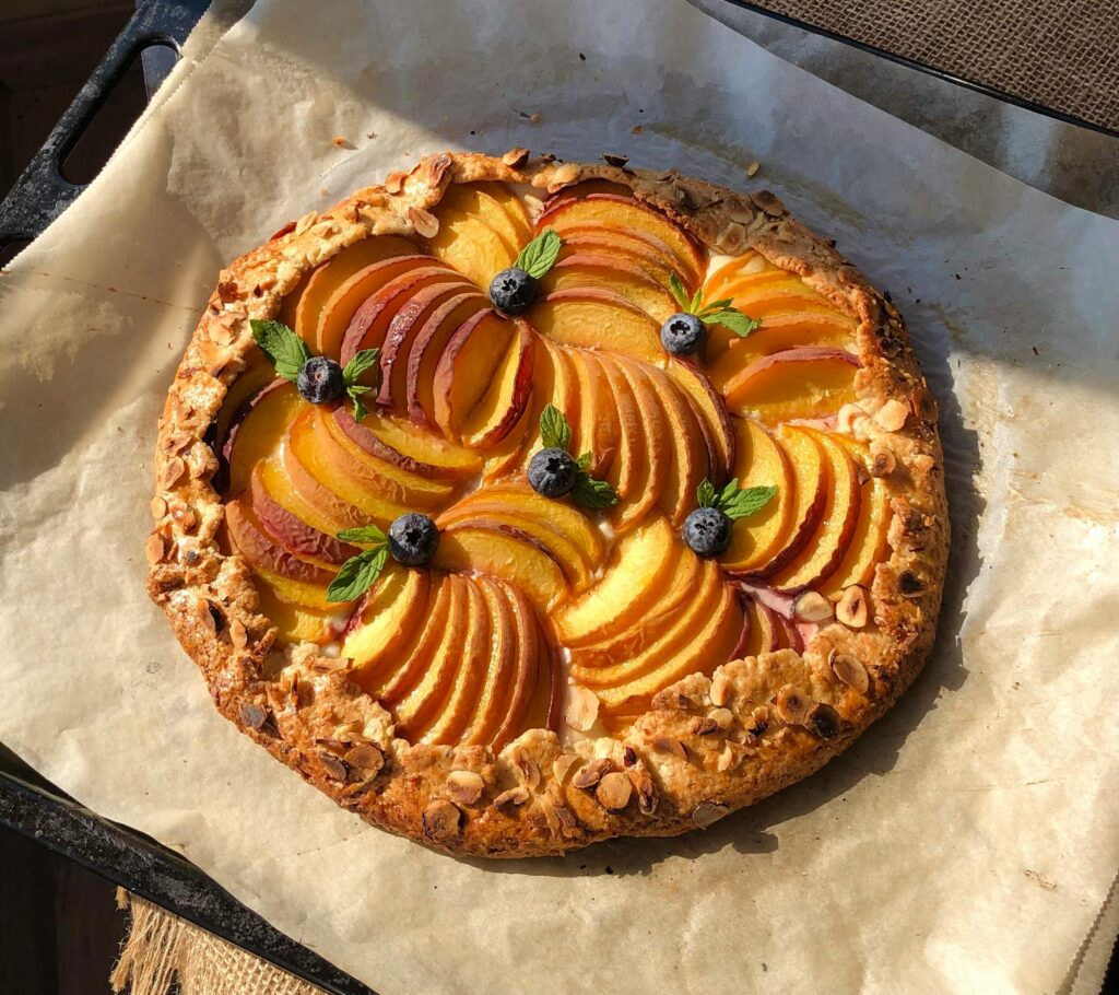 Freshly baked peach tart topped with blueberries, perfect for a summer dessert.