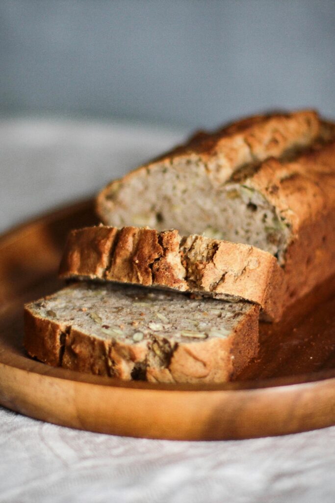 Freshly baked whole wheat bread sliced on a wooden plate, showcasing its wholesome texture.