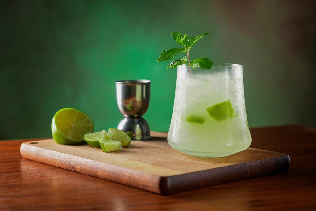 Chilled lemonade with fresh lime and mint garnish on a wooden board, perfect for a summer refreshment.