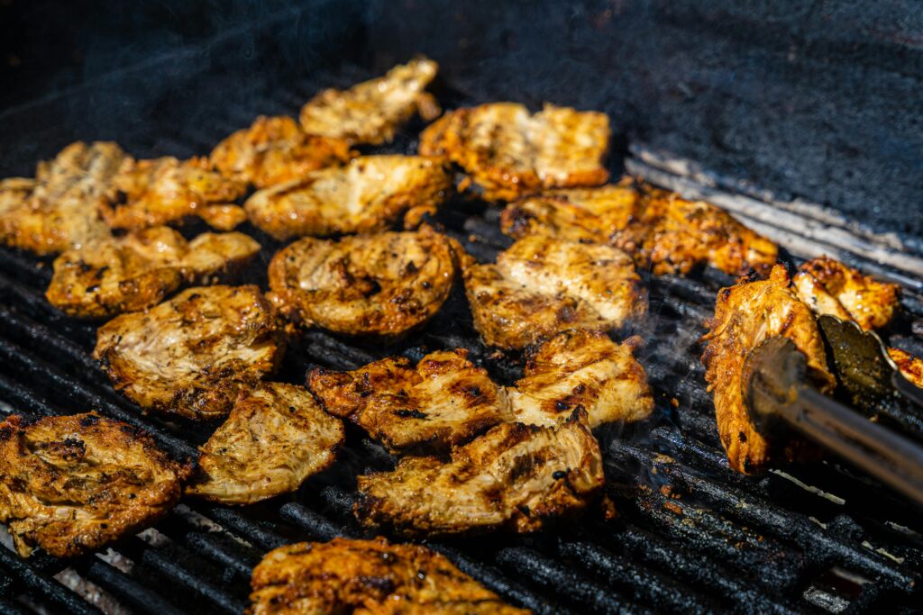 Close-up of juicy chicken grilling on a barbecue, capturing the sizzling and smoky flavors of outdoor cooking.