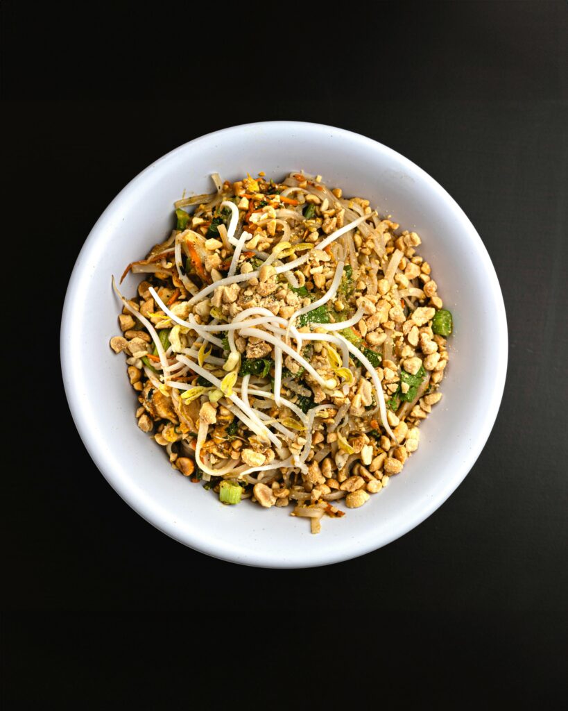 Delicious Thai vermicelli with vegetables and peanuts in a white bowl.