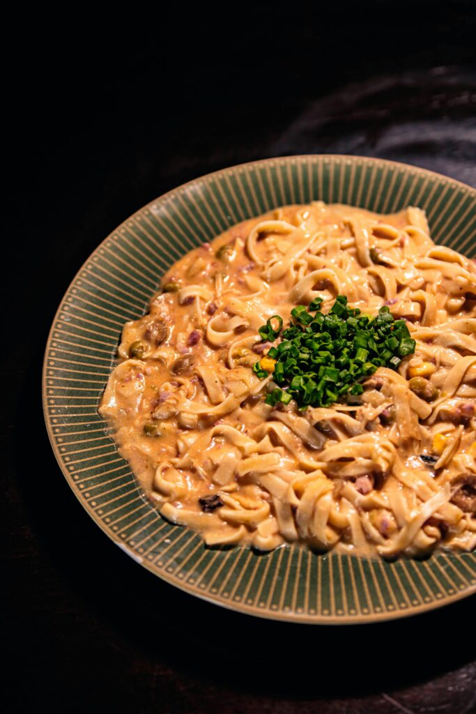 Close-up of creamy pasta topped with fresh chives, highlighting a gourmet culinary delight.