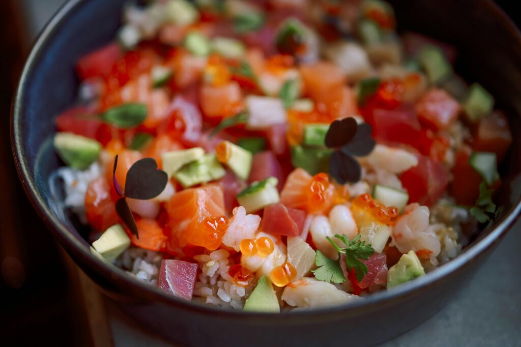 Vibrant poke bowl with fresh salmon, tuna, avocado, and roe for a healthy meal.