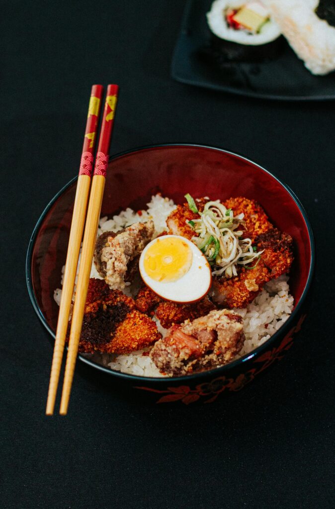 Delicious Japanese rice bowl with crispy fried chicken and a boiled egg, garnished beautifully.