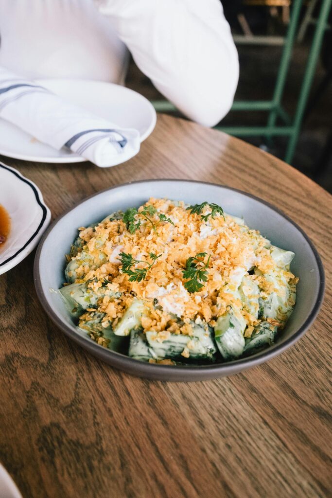 Delicious cucumber salad topped with crispy crumbs in a bowl on a wooden table.
