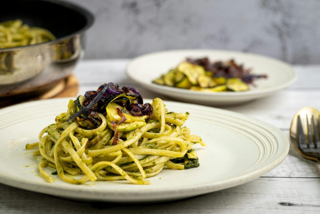 A flavorful zucchini pasta dish with pesto, garnished with red onions, perfect for a gourmet meal.
