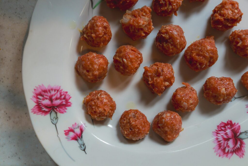 Tasty homemade meatballs arranged on a floral-decorated plate, perfect for food lovers.