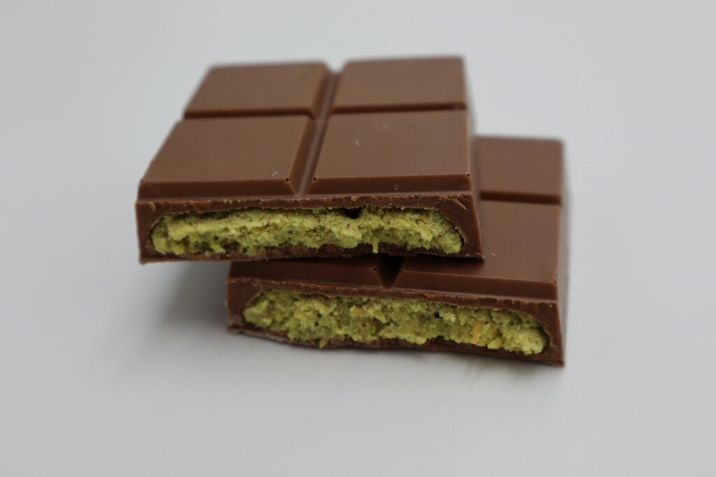 Close-up of a milk chocolate bar with pistachio filling, showcasing its delectable texture.