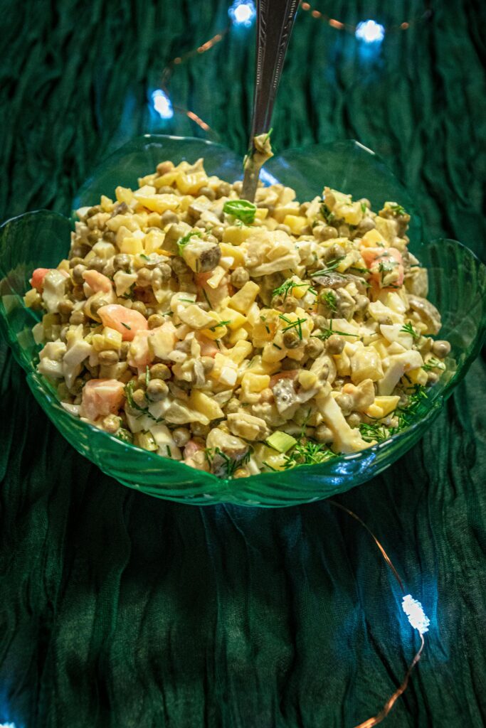 Delicious Russian Olivier salad with vegetables and mayonnaise in a green bowl, perfect for festive occasions.