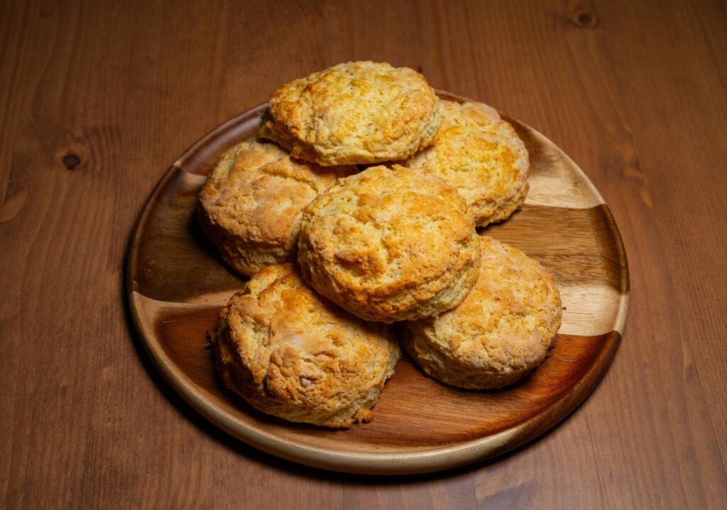 Golden, homemade biscuits arranged on a wooden plate, ready to enjoy.