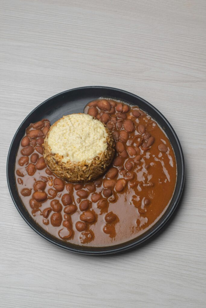 Aerial shot of a rice and bean dish with rich sauce on a black plate, perfect for cooking blogs.