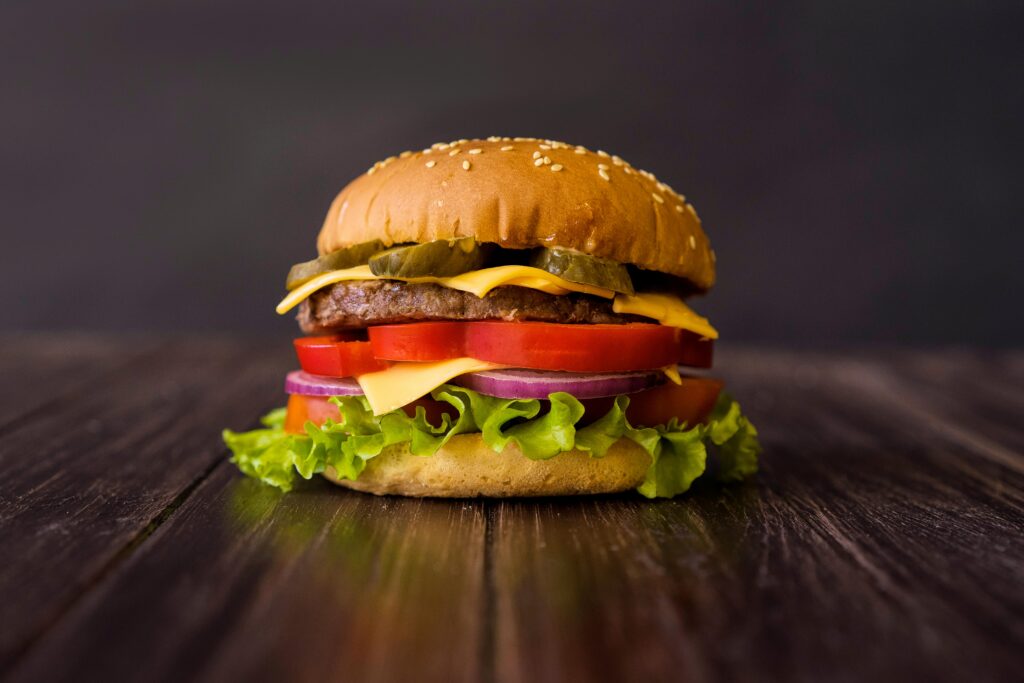 Close-up of a mouth-watering cheeseburger with fresh ingredients on a wooden table.