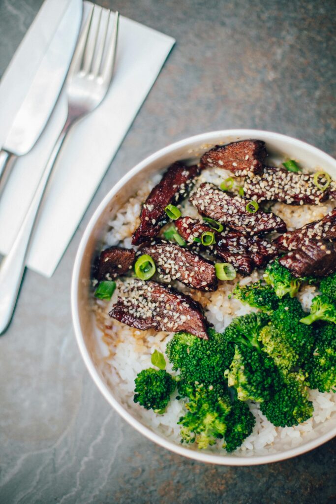 Delicious beef and broccoli served on rice with sesame seeds, top view.